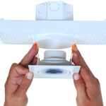 Mãos fazendo a instalação rápida do spot de LED na caixa de luz de embutir utilizando as molas de fixação.